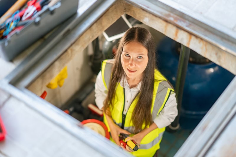 A portrait of a female maintenance worker checking and fixing pipes and water pumping machines.