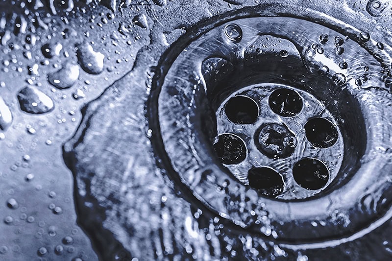 4 Reasons to Clean Your Drains Before the Holidays. Water going down a sink drain.