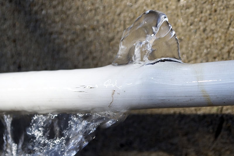 Your Complete Guide to Finding and Fixing Water Leaks. Photo of a broken pipe with water flowing out of it.
