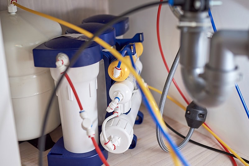 What Is Reverse Osmosis? Photo of a water system underneath a kitchen sink.