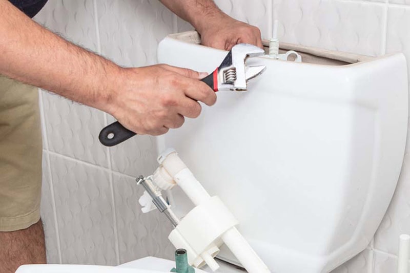 Why Is My Toilet Bubbling? What It Means and What You Should Do. Photo of a plumber performing maintenance on a toilet.